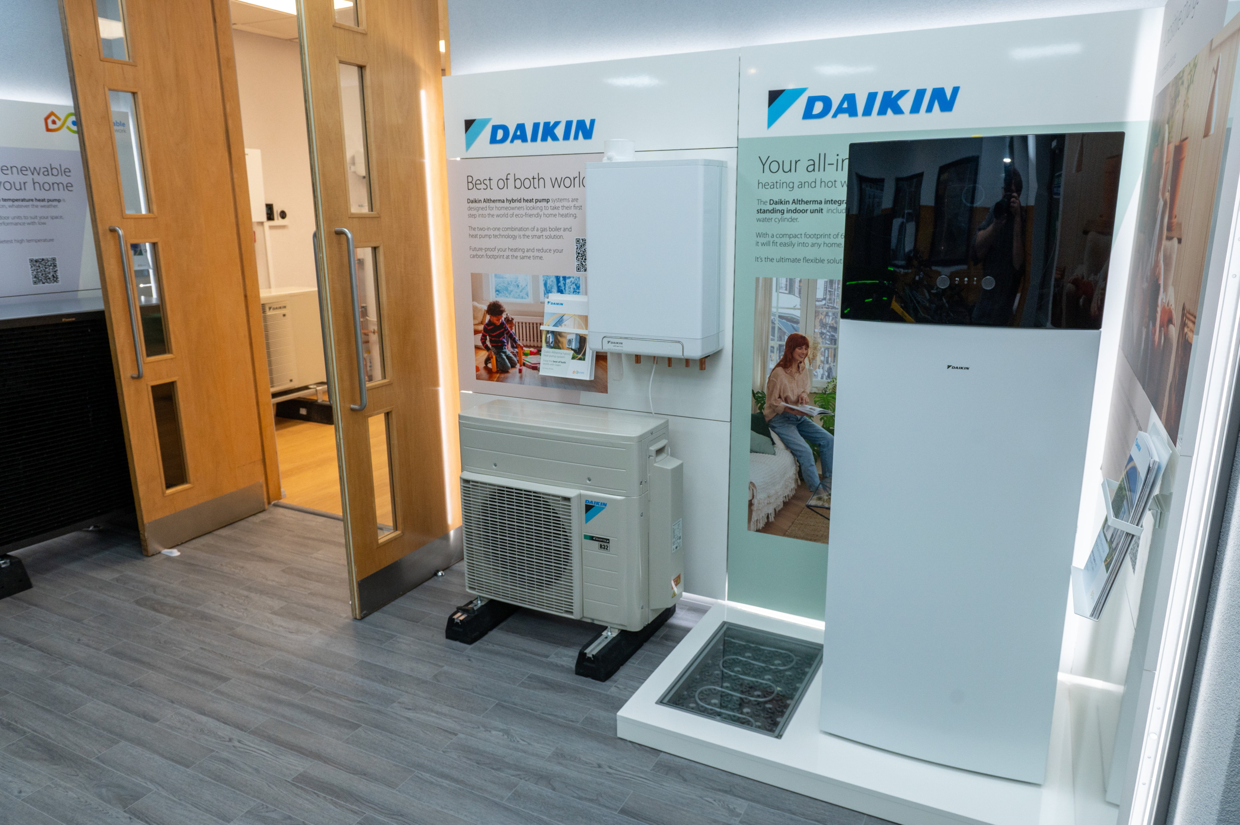 Daikin heating display in the showroom featuring an Altherma hybrid heat pump, outdoor condenser unit, and an all-in-one heating and hot water cylinder